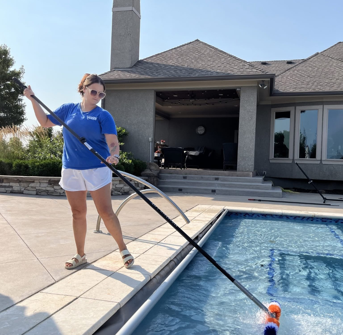 Icon Pools technician skimming a backyard pool